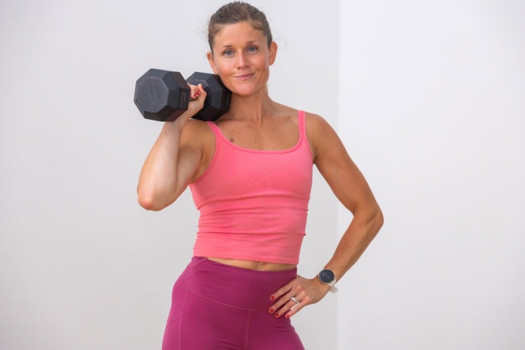 woman holding dumbbell on shoulder